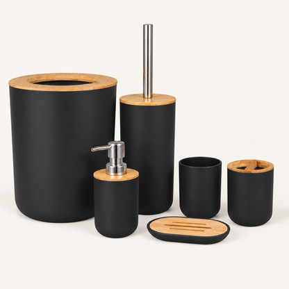 Black six-piece bamboo bathroom accessories set with open-top waste bin, silver pump dispenser, toothbrush holder, tumbler, toilet brush and soap dish on warm cream background